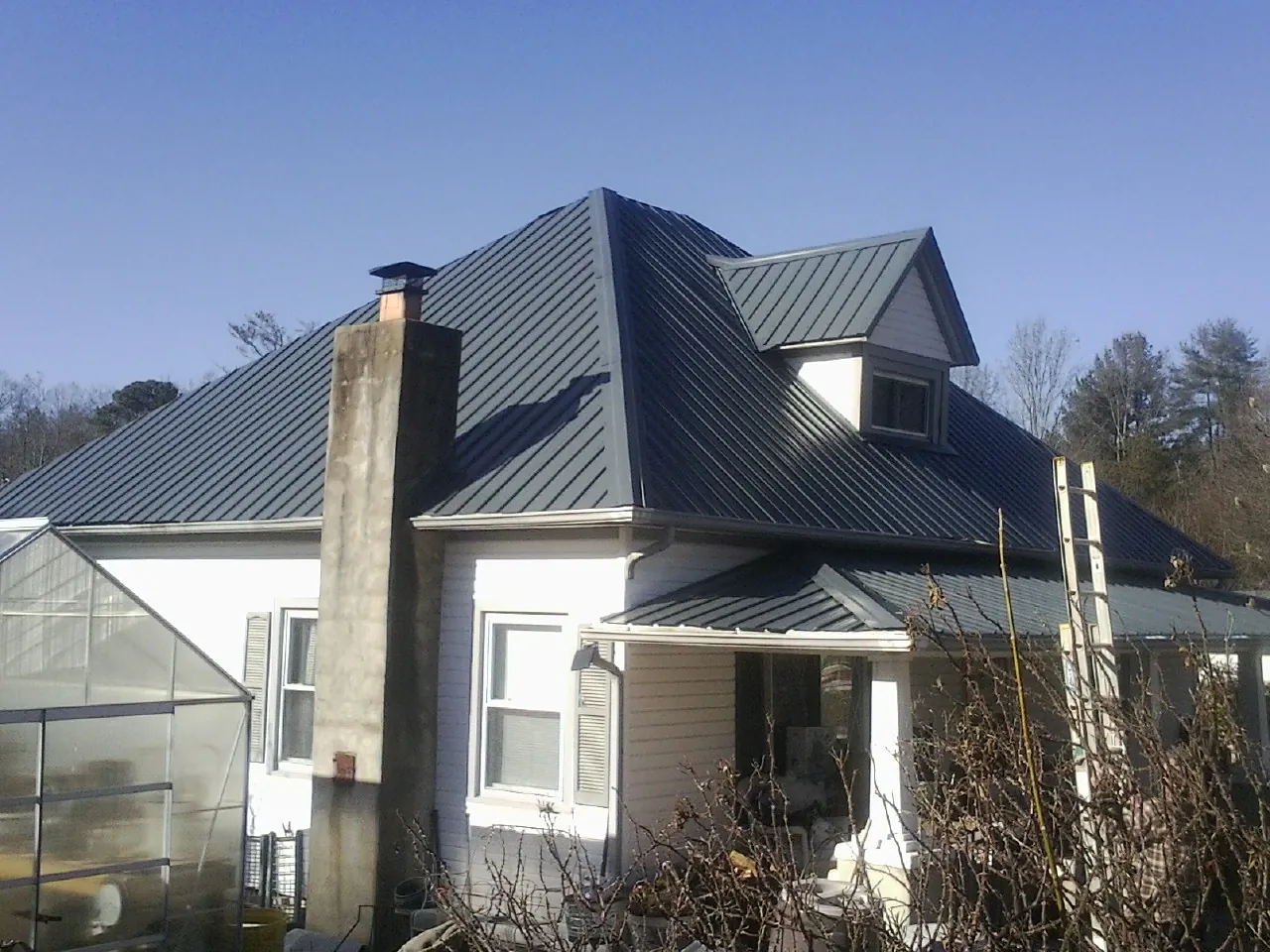 Dark blue standing seam metal roof on a white farmhouse with dormer — Slate & Tile Roof Repair by Roofing Brothers in Paris