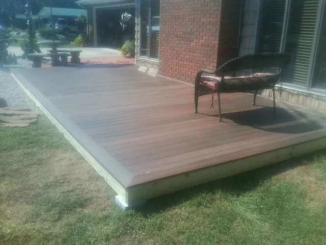 New wood deck and wicker chair beside a brick house in Paris
